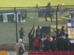 England coach Brendon McCullum climbs up a fence for Pakistan fans