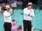 Umpires Chris Gaffaney (L) and Paul Reiffel check a light meter reading during a delay due to bad light on Day 1 of the 3rd Test between Australia and South Africa