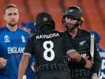 England's Liam Livingstone holds hand with teammate Dawid Malan and watches New Zealand's Rachin Ravindra and Devon Conway celebrate at the end of the ICC Cricket World Cup opening match against New Zealand in Ahmedabad, India