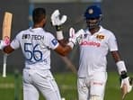 Dinesh Chandimal celebrates after scoring a century (100 runs) with Angelo Mathews (R) during Day 2 of the one-off Test cricket match between Sri Lanka and Afghanistan.