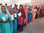 Voters show their identity cards as they wait in a queue at a polling station to cast their votes during the sixth phase of the Lok Sabha elections.