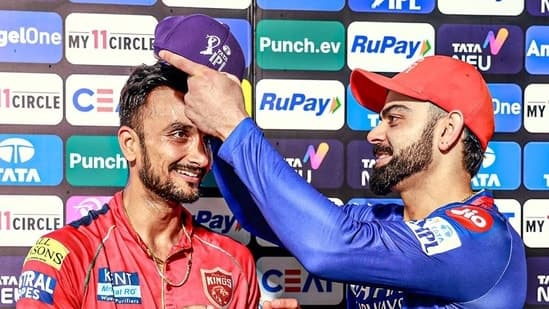 Punjab Kings' Harshal Patel receives the IPL Purple Cap from Royal Challengers Bengaluru's Virat Kohli 

