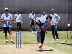Shivam Dube bowls during a practice session as coach Rahul Dravid and teammates look on.