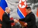 Russian President Vladimir Putin, left, and North Korea's leader Kim Jong Un exchange documents during a signing ceremony of the new partnership
