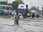 Vehicles and commuters are struggling to navigate through knee-deep water on NH-48 near Narsinghpur Village in Gurugram.